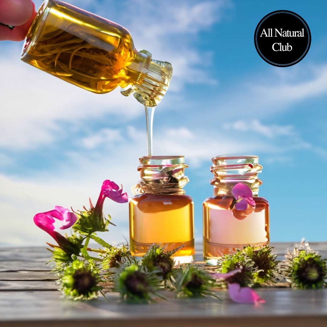 Image of bee balm oil being poured into small ornate glass jars with bee balm growing around the table. A beautiful sky in the background.