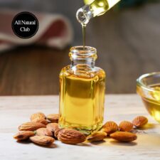 Image of almond oil being poured into small ornate glass jars with almonds scattered on the table.